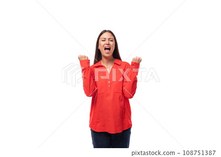 young brunette leader woman with long hair dressed in a red shirt tells the news by shouting on a 108751387