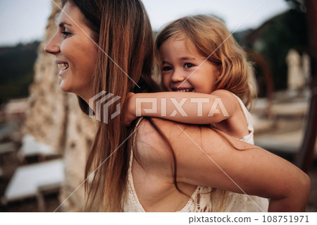 Cute young daughter on a piggy back ride with her mother. Cute young daughter on a piggy back ride with her mother. 108751971