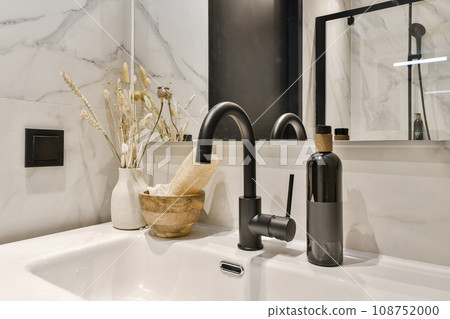 a bathroom sink with some flowers in the bowl and a mirror on the wall behind it is a black fae a bathroom sink with some flowers in the bowl and a mirror on the wall behind it is a black fae 108752000