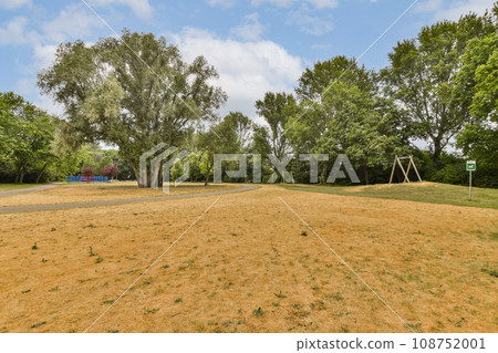 a grassy field with trees and a blue sky in the background on a sunny day at an outdoor play area a grassy field with trees and a blue sky in the background on a sunny day at an outdoor play area 108752001
