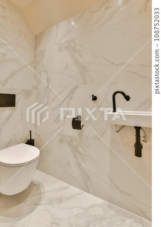 a bathroom with marble walls and white fixtures on the wall, there is a toilet in the corner next to the sink a bathroom with marble walls and white fixtures on the wall, there is a toilet in the corner next to the sink 108752033
