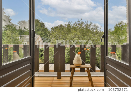 an outside area with wood flooring and wooden doors leading to the patio, looking out onto trees in the distance an outside area with wood flooring and wooden doors leading to the patio, looking out onto trees in the distance 108752371