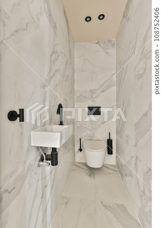 a bathroom with white marble walls and black fixtures on the wall, there is a toilet next to the sink a bathroom with white marble walls and black fixtures on the wall, there is a toilet next to the sink 108752406