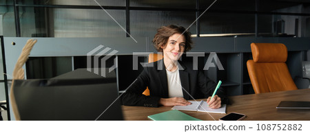 Portrait of successful brunette woman in suit, corporate manager in office, writing, preparing documents for meeting, reading case 108752882