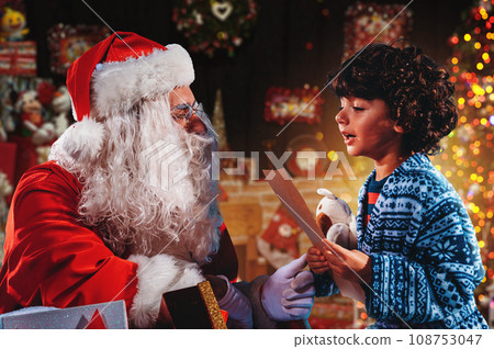 Santa Claus listens the gifts request of a child for Christmas 108753047