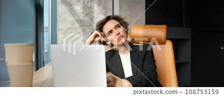 Portrait of thinking woman, corporate businesswoman in her office, sitting with laptop, looking up with thoughtful face, pondering Portrait of thinking woman, corporate businesswoman in her office, sitting with laptop, looking up with thoughtful face, pondering 108753159