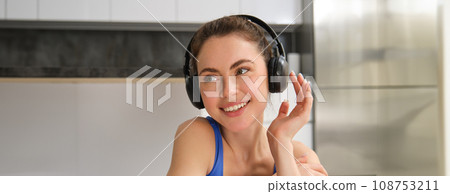 Close up portrait of attractive young smiling woman, workout, doing fitness training, listening music in headphones 108753211