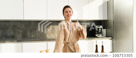 Portrait of happy young woman preparing vegetarian dinner, showing thumbs up, wife cooking in kitchen and smiling, recommending product, chopping vegetables for healthy salad Portrait of happy young woman preparing vegetarian dinner, showing thumbs up, wife cooking in kitchen and smiling, recommending product, chopping vegetables for healthy salad 108753305