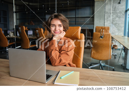 Portrait of young female entrepreneur, businesswoman in office, sitting with laptop, working on project, creating content for company social media 108753412