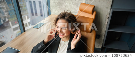 Image of woman in conference room, businesswoman working in her office in front of the window, answering a phone call and laughing 108753624