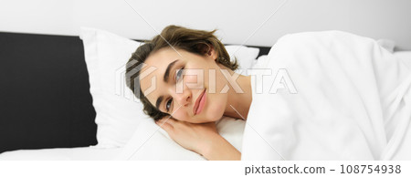 Close up portrait of smiling young woman, relaxing, lying in bed with calm, tender face expression, resting, going to sleep 108754938