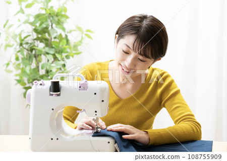 A woman sewing with a sewing machine 108755909