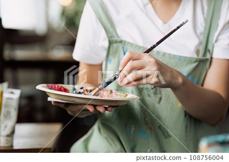 Female artist hold color palette and paintbrush for painting during hobby workshop Female artist hold color palette and paintbrush for painting during hobby workshop 108756004