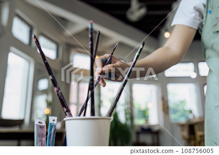 Female artist hold color palette and paintbrush for painting during hobby workshop Female artist hold color palette and paintbrush for painting during hobby workshop 108756005