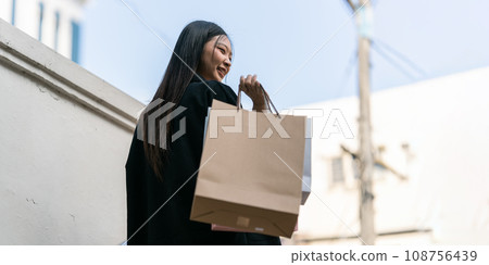 Young asian woman in shopping. Fashion woman in black with shopping bag walking around the city after shopping. Black friday 108756439