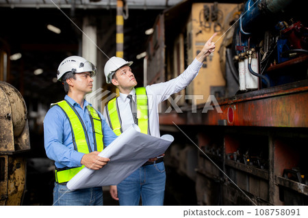 Team young caucasian engineer man checking train looking blueprint in station. 108758091