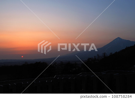 Evening view of Mt. Bandai. The bright red sun, the silhouette of the mountains, and the gradation of the sky from orange to blue are impressive and beautiful. Evening view of Mt. Bandai. The bright red sun, the silhouette of the mountains, and the gradation of the sky from orange to blue are impressive and beautiful. 108758284