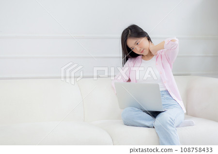 Beautiful young asian businesswoman sitting on sofa and working from home and break. 108758433