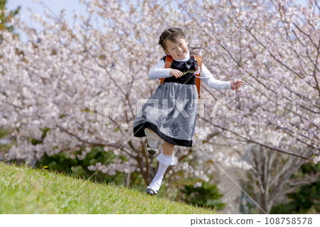 背著書包的一年級學生穿過櫻花盛開的公園 108758578