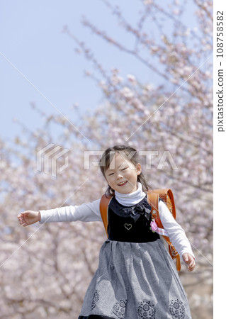 背著書包的一年級學生走過櫻花盛開的公園 108758582