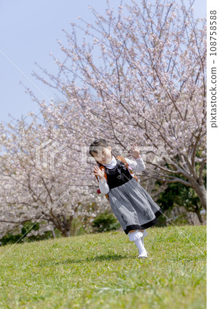 背著書包的一年級學生走過櫻花盛開的公園 108758588