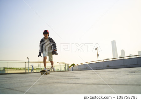 teenage asian child skateboarding outdoors on a pedestrian bridge 108758783