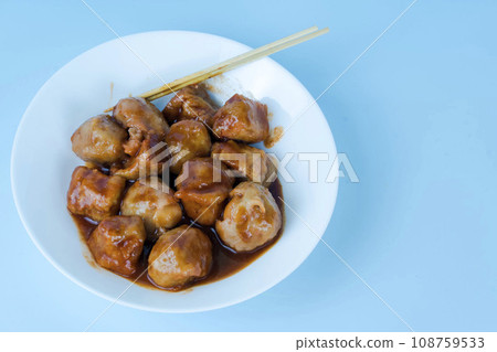 A plate of Pentol Siomay, a traditional Indonesian dumpling with peanut sauce, on a blue background 108759533