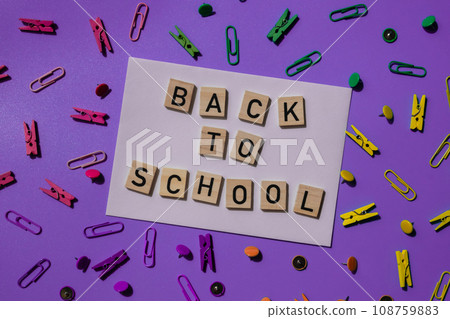 Educational greeting announcement for students and teacher. Saying BACK TO SCHOOL text on wooden blocks on creative vivid background with stationery supplies around. Concept of new school year 108759883