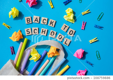BACK TO SCHOOL message inscription text on wooden blocks on creative colorful blue background with stationery supplies around. Copy space Educational greeting announcement for students and teacher BACK TO SCHOOL message inscription text on wooden blocks on creative colorful blue background with stationery supplies around. Copy space Educational greeting announcement for students and teacher 108759886