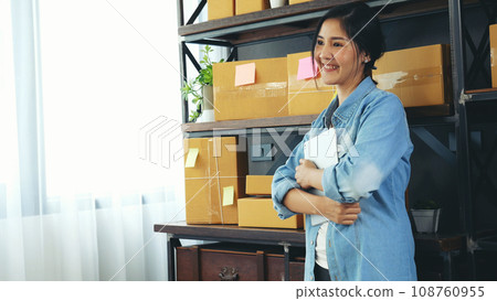 Asian woman startup small business at home office. Online seller entrepreneur young asian woman use tablet checking online order. Woman using tablet check stock goods supply delivery package shipping Asian woman startup small business at home office. Online seller entrepreneur young asian woman use tablet checking online order. Woman using tablet check stock goods supply delivery package shipping 108760955
