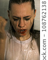Portrait of a young girl with dripping makeup standing in the shower. Vertical Shot 108762138