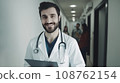 Hospital. Health care. Portrait of young smiling 30-year-old bearded caucasian man doctor wearing white medical coat with stethoscope around his neck, looking at camera. Hospital Corridor, AI 108762154
