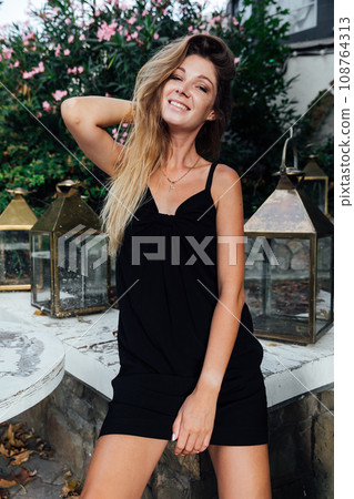 Beautiful slender woman in black summer dress Beautiful slender woman in black summer dress 108764313