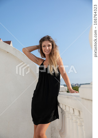 Beautiful slender woman in black summer dress Beautiful slender woman in black summer dress 108764323