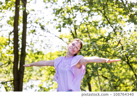 Forest Freedom: Woman Embraces Sunlit Woods Forest Freedom: Woman Embraces Sunlit Woods 108764340