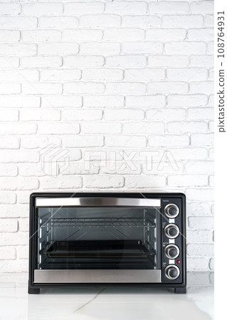 Mini electric oven against white brick wall in the kitchen Mini electric oven against white brick wall in the kitchen 108764931