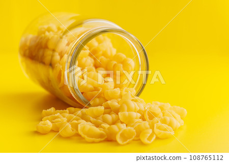 Uncooked gnocchi pasta. Raw italian pasta in jar on yellow background. 108765112