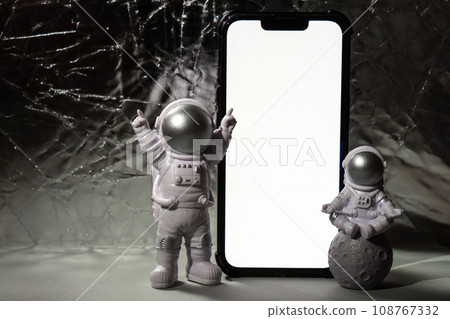Plastic toy figure astronaut with mobile phone white screen for your advertisement Copy space. Concept of out of earth travel, private spaceman commercial flights missions and Sustainability 108767332