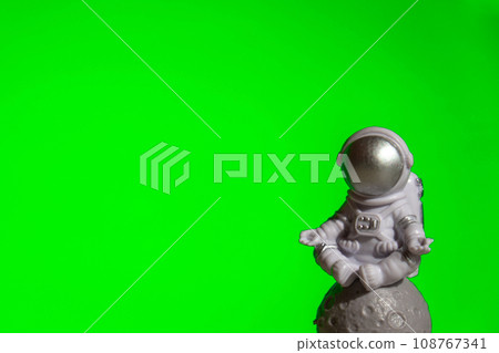 Plastic toy astronaut on green chroma key background Template Mock up Copy space. Concept of out of earth travel, private spaceman commercial flights missions and Sustainability 108767341