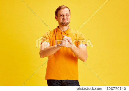 Portrait of handsome young man, student wearing casual outfit with proud face expression and clapping hands isolated yellow studio background. 108770140