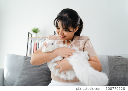Happy Woman Playing with Cat in Cozy Living Room at Home. 108770228