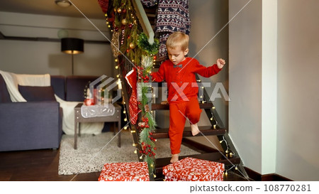 Two boys rushing down the stairs in living room on Christmas morning to open gifts and presents from Santa on New Year. Family celebrations on winter holidays. Two boys rushing down the stairs in living room on Christmas morning to open gifts and presents from Santa on New Year. Family celebrations on winter holidays. 108770281