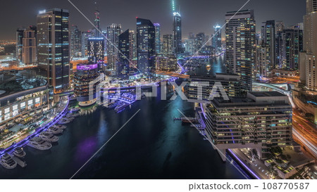 Aerial view to Dubai marina skyscrapers around canal with floating boats night timelapse Aerial view to Dubai marina skyscrapers around canal with floating boats night timelapse 108770587