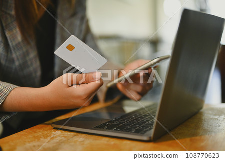 Young businesswoman holding credit card using mobile phone doing online banking transaction or shopping in online store Young businesswoman holding credit card using mobile phone doing online banking transaction or shopping in online store 108770623