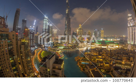 Skyscrapers rising above Dubai downtown day to night timelapse surrounded by modern buildings aerial top view 108770643