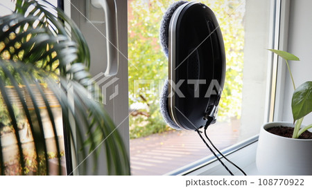 Robot window cleaner work on dirty window. Cleaning the house with smart devices. Automatic vacuum robots for cleaning windows, an assistant for the home 108770922