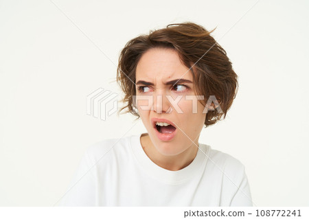 Portrait of offended woman, frowning and looking with dismay aside, complaining at someone, looks frustrated, stands over white background Portrait of offended woman, frowning and looking with dismay aside, complaining at someone, looks frustrated, stands over white background 108772241