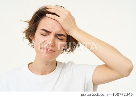 Portrait of woman touches her head, looks upset or disappointed, forgot something, has headache, migraine, standing over white background Portrait of woman touches her head, looks upset or disappointed, forgot something, has headache, migraine, standing over white background 108772346