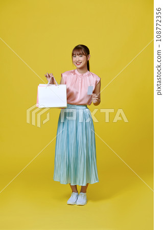 Asian happy female woman girl holds colourful shopping packages and cashless credit card payment 108772356