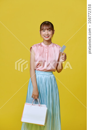 Excited smile Asian woman looking mobile phone holding shopping bag show credit card payment banking shopping online 108772358